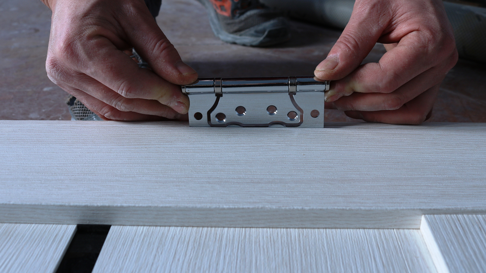 Мужчина примеряет петлю межкомнатной двери